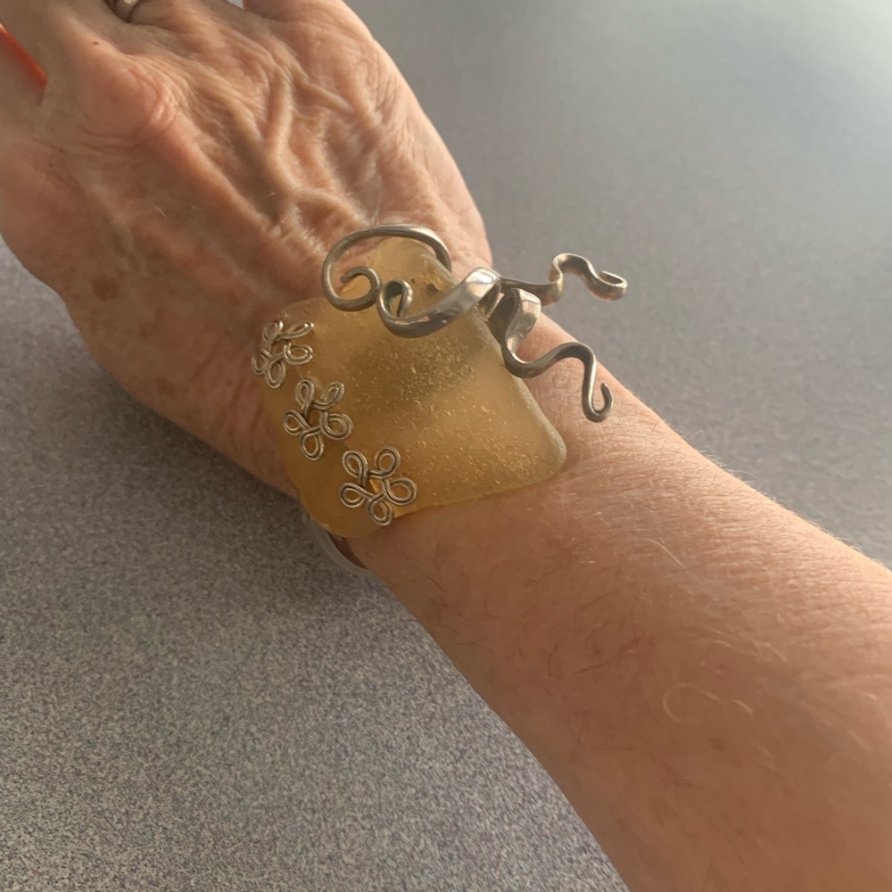 A vintage handcrafted artisan cuff bracelet featuring a large piece of sea glass